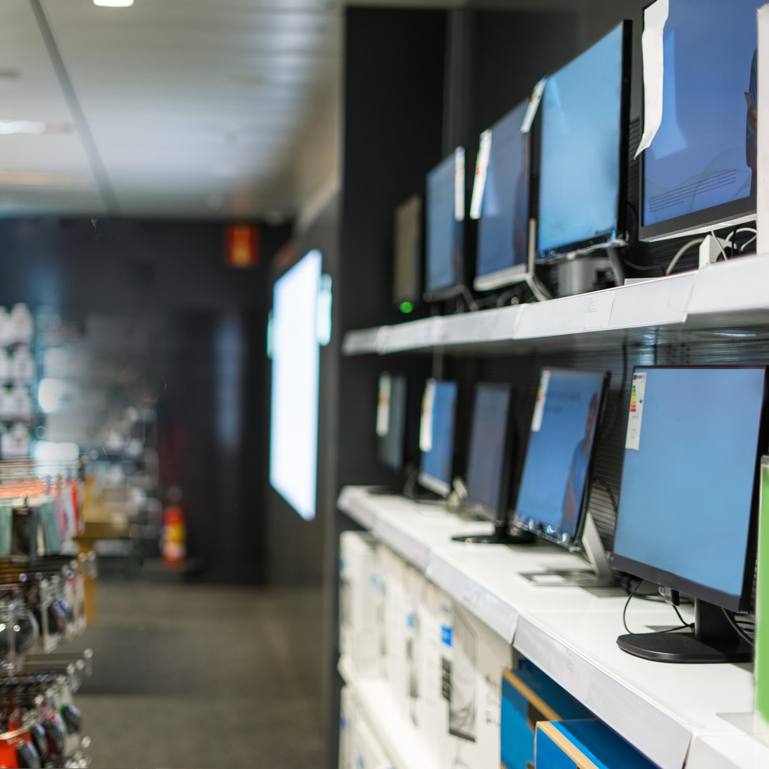 Side view of concentrated male buyer picking computer monitor while standing in electronics store